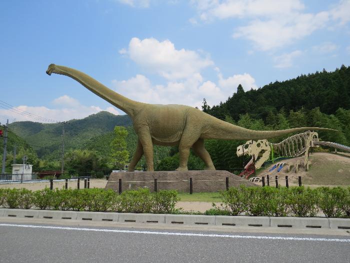 丹波竜の里公園モニュメント まんなかに首と尻尾の長い恐竜のモニュメントがある